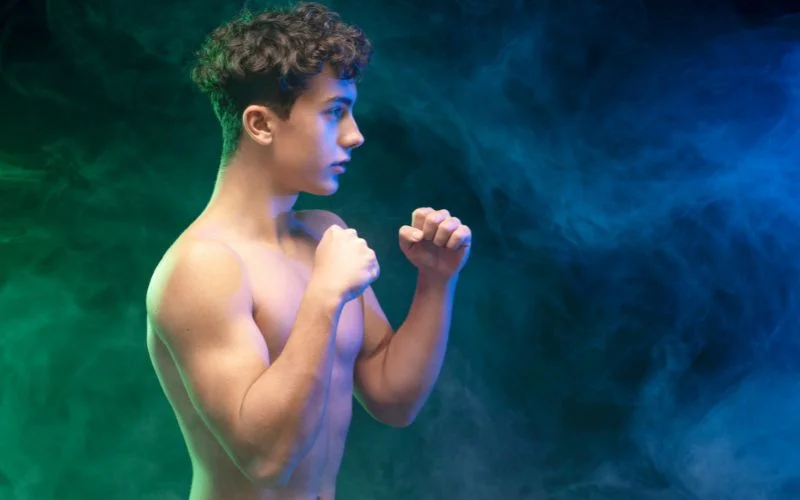 Athletic male nude model posing outdoors with defined physique and dramatic natural lighting