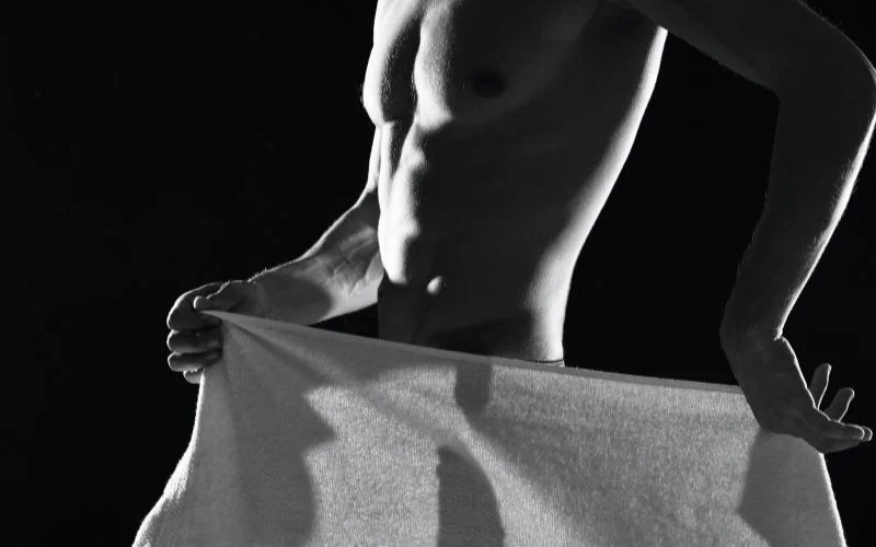 Vintage-inspired male nude photography with draped fabric and soft shadows