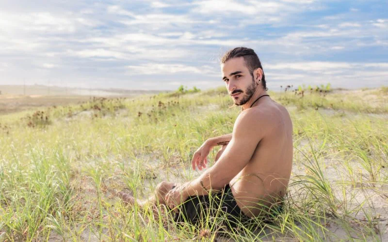 Male nude model sitting on the ground in a relaxed artistic portrait pose