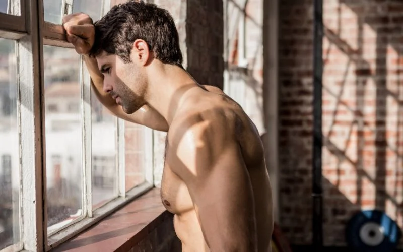 Male nude pose with raised arms emphasizing body shape and muscle definition
