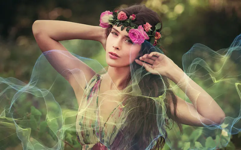 Smoke overlay effect on portrait of woman wearing flower crown in green forest