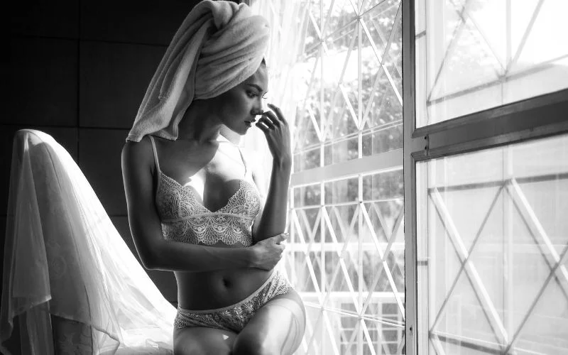Black and white wedding boudoir nude portrait of a bride by a window in soft lace lingerie