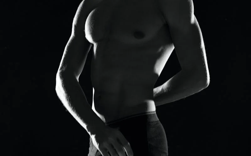 Partial silhouette male boudoir pose with side lighting creating a mysterious atmosphere