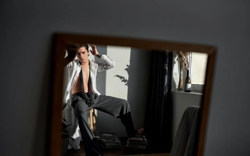Mirror reflection portrait featuring stylish men boudoir poses and soft ambient lighting