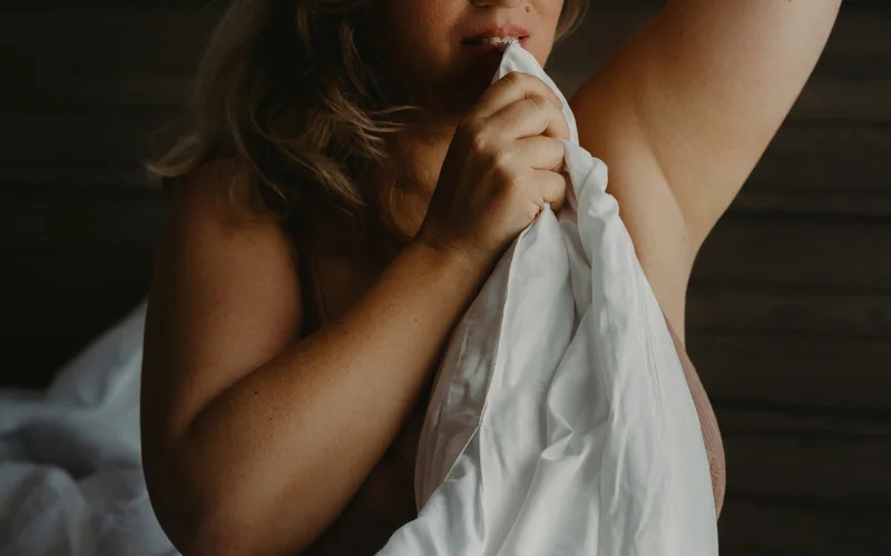 Woman wrapped in white bedsheets, artistic nude pose using fabric for tasteful coverage