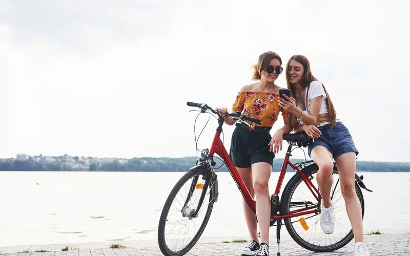 Two friends riding bicycles side by side on an open path