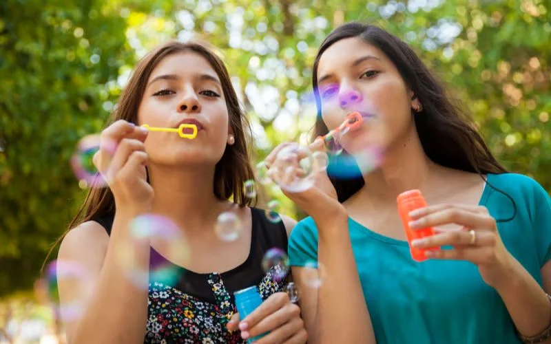 Girl best friends blowing bubbles together in a fun and whimsical photoshoot pose