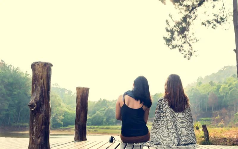 Two best friends sitting and chatting at a scenic outdoor destination