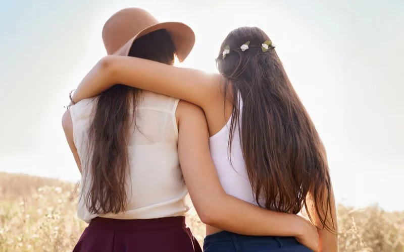 Two best friends standing facing back in a classic bestie photo pose