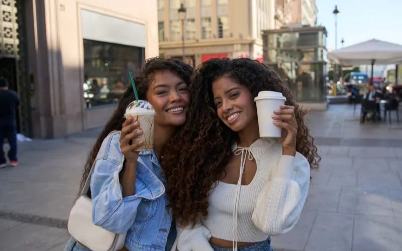 Two friends sitting across each other enjoying coffee at a cafe
