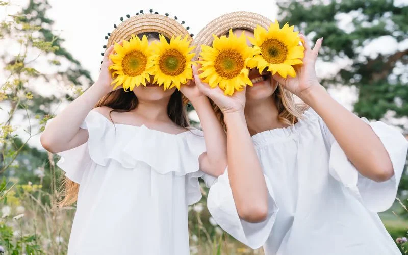 Two friends covering their faces with flowers in a creative best friend photoshoot pose