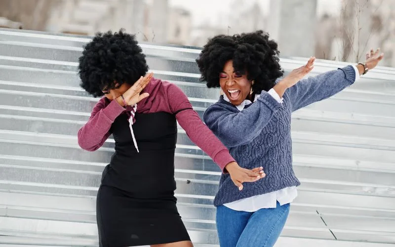 Two best friends dancing together outdoors in a joyful and candid friend pose