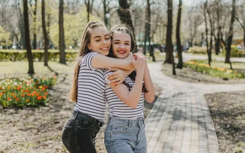 One best friend hugging the other from behind in a sweet and candid photo