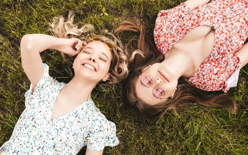 Best friends lying on the ground and looking up at the camera in a fun top-down photo pose