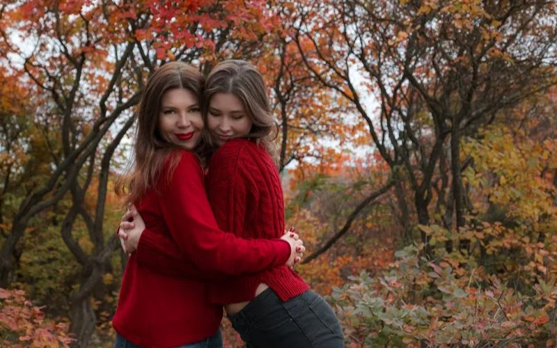 Two best friends posing among autumn leaves in a dreamy seasonal photoshoot