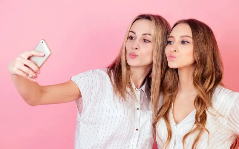 Two best friends pouting and taking a selfie together in a fun friend photo pose