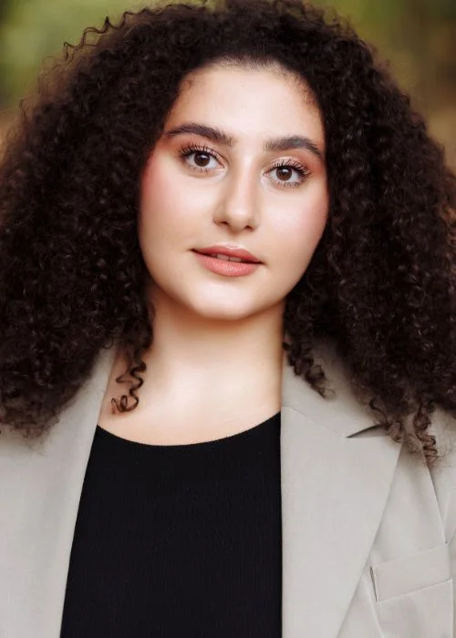 Close-up corporate headshot of a woman with a natural and confident expression.
