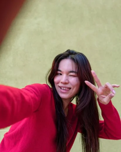 Person making a funny expression and playful gesture while capturing a lighthearted selfie.