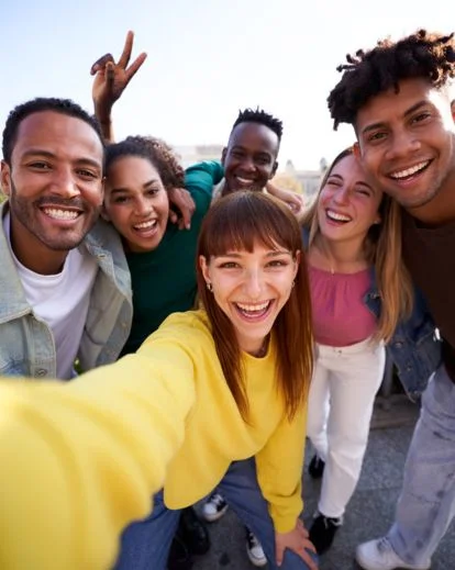 Group of friends smiling and posing together for a fun group selfie during a social gathering.