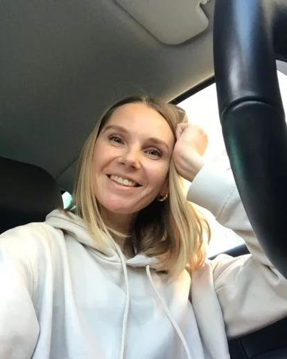 Person taking a selfie inside a car using natural window light, demonstrating flattering selfie poses in car settings.