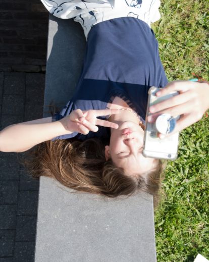 Person lying on the floor, grass, or bed while taking a creative overhead selfie with a relaxed vibe.