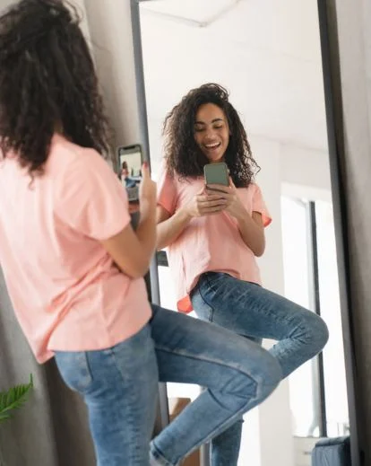 Person taking a stylish mirror selfie in a bedroom, showcasing one of the most popular mirror selfie poses for social media.