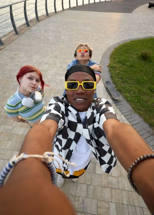 Group of friends taking a creative overhead selfie with extended arms and playful expressions in a park.