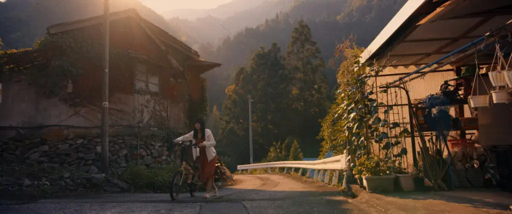 Warm-toned photo of two people walking down a village path at golden hour