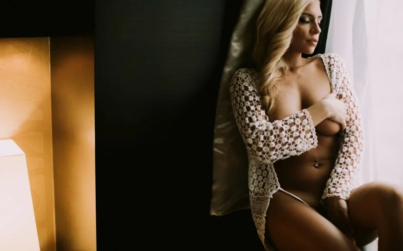 Elegant boudoir photo shoot with soft window light and romantic bedroom setting