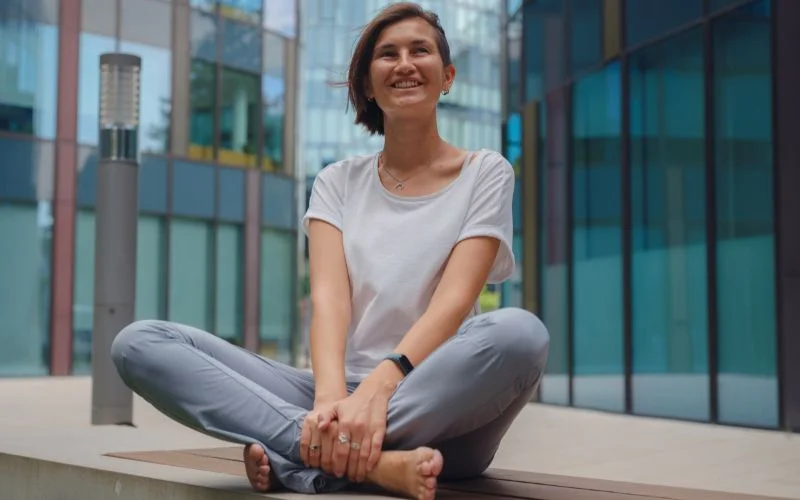 Relaxed crossed-leg sitting pose with upward gaze and natural lighting