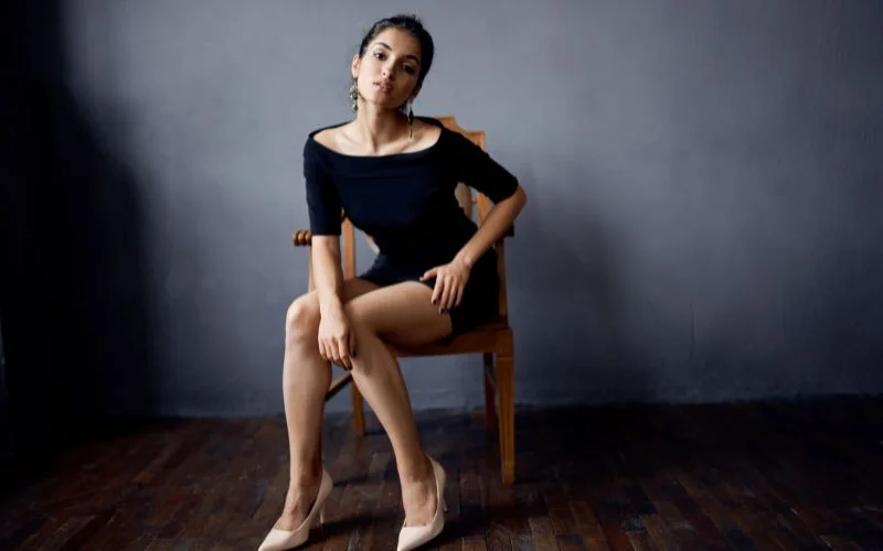 Creative leaning-forward portrait pose using a stylish prop for added depth