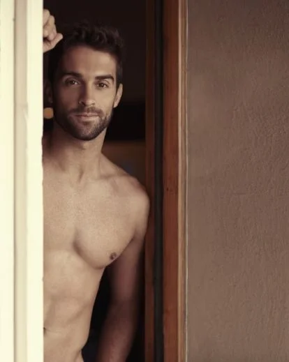 Confident men boudoir pose leaning against a doorway with relaxed posture