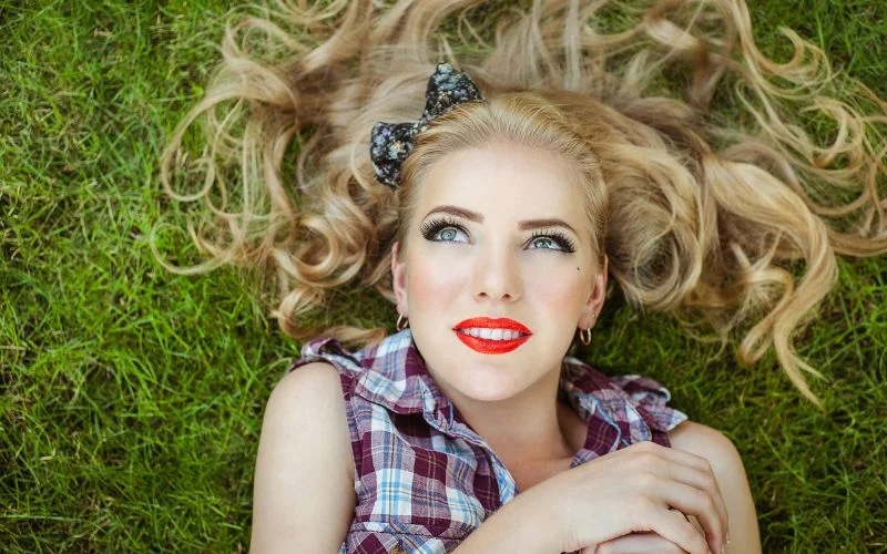 woman lying down gracefully on grass in a classic pin up pose
