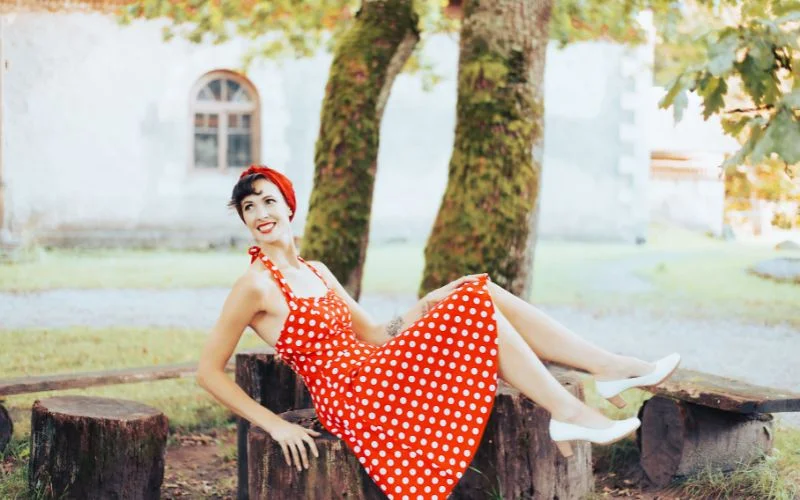 woman reclining gracefully on a vintage chaise lounge in a classic pin up sitting pose