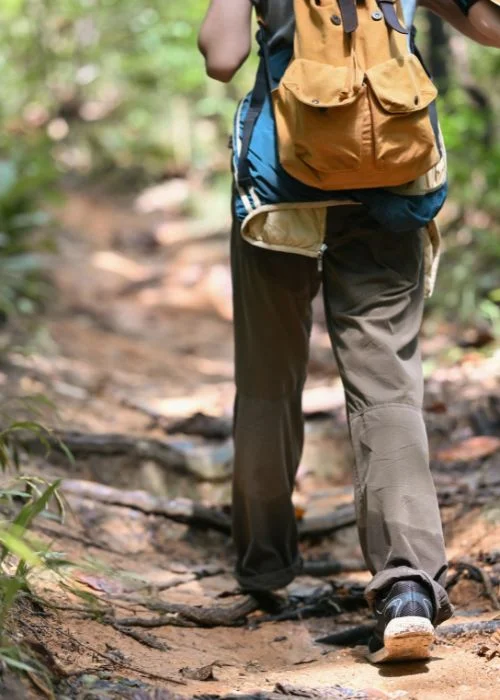 Close-up of a hiker walking along a woodland path with a backpack, capturing a candid hiking photography scene.