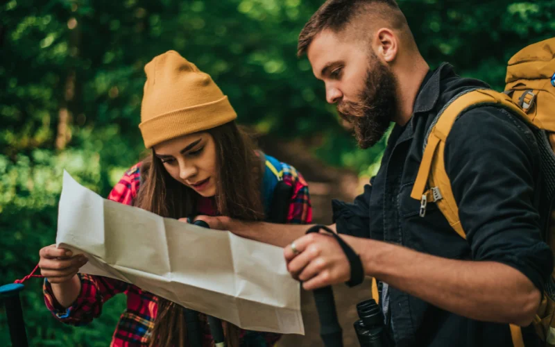Adventurers checking a trail map while standing on a hiking path, creating a natural and candid outdoor portrait.