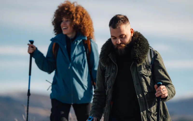 Couple hiking together on a scenic trail while enjoying breathtaking mountain views.