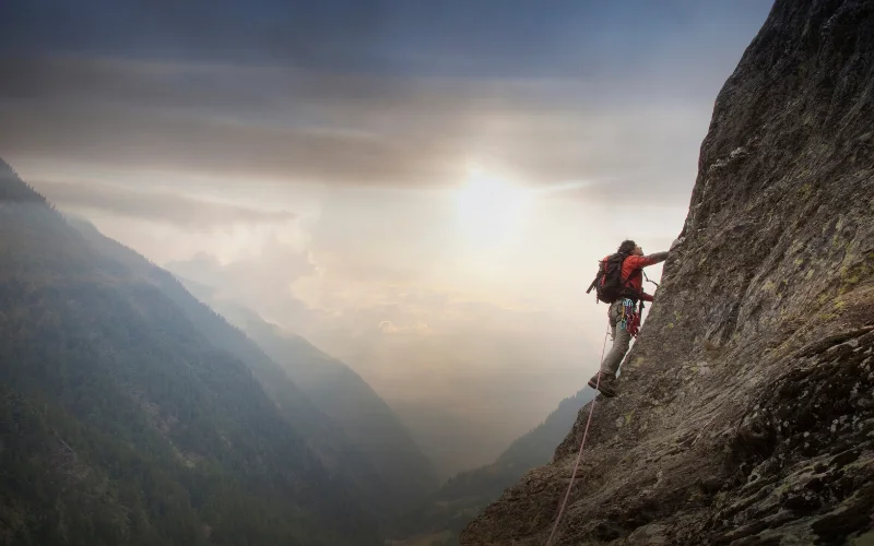 Adventurer climbing a rocky cliff face during an exciting outdoor adventure and hiking photography session.