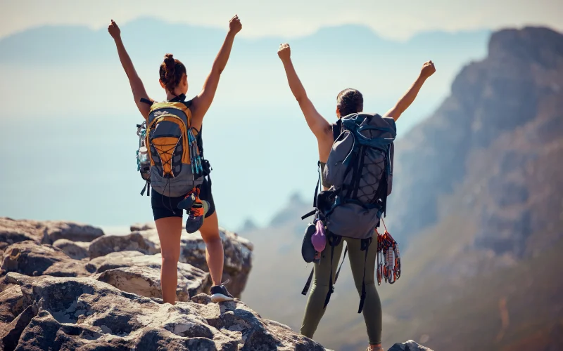 Hiker standing on a mountain viewpoint with arms wide open, embracing the surrounding wilderness in a classic hiking pose.