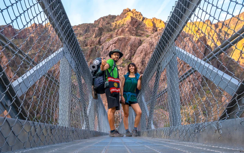 Hikers walking across a wooden bridge surrounded by lush greenery, perfect for creative hiking picture poses.
