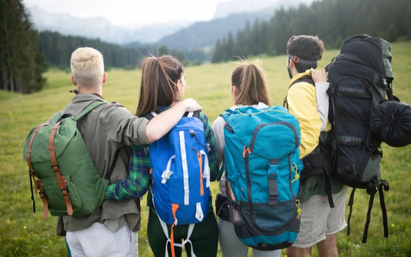 Outdoor enthusiasts posing with a backpack while looking toward the mountains, ideal for hiking portrait photography inspiration.