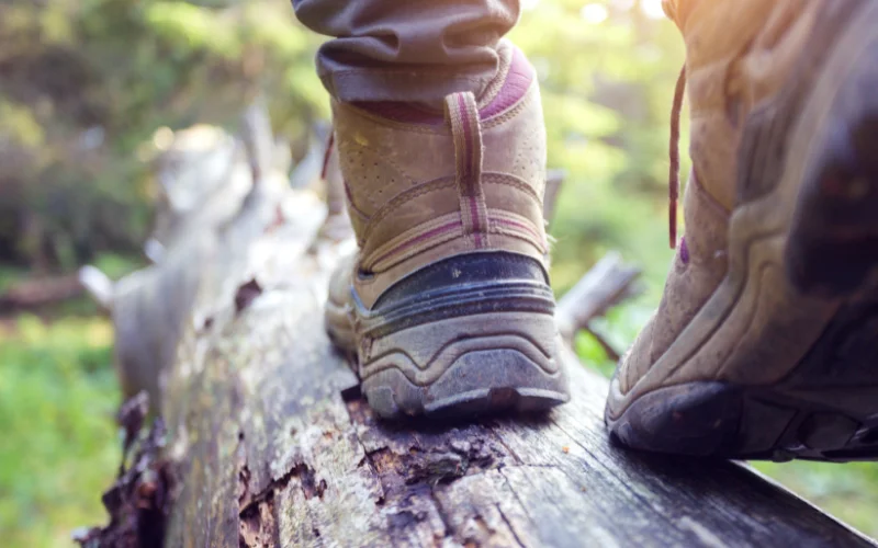 First-person view of hiking boots and legs extending toward a stunning mountain landscape.