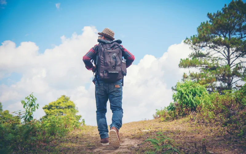 Hiker walking confidently along a mountain trail surrounded by scenic landscapes during a hiking photography session.