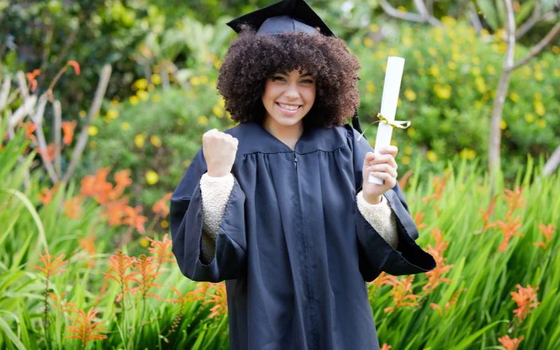 Graduation photo poses of a graduate walking forward through a garden, holding her diploma