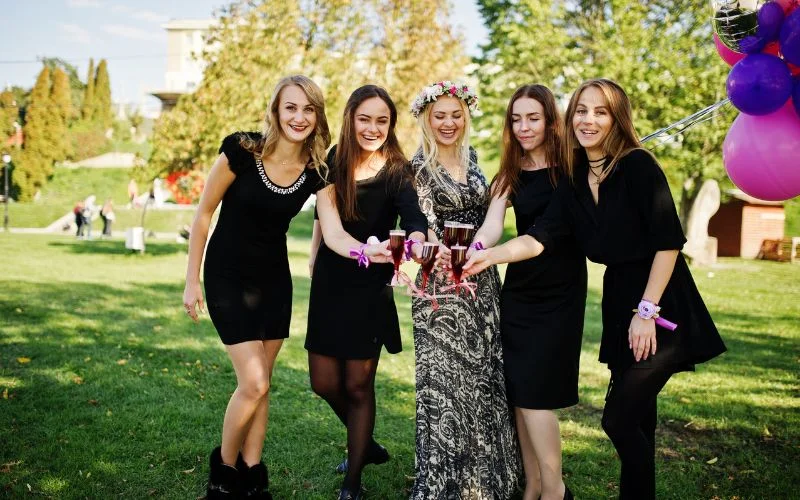 Group of friends in black outfits posing together outdoors with balloons