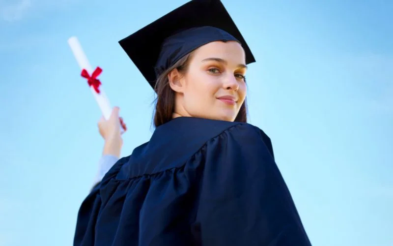 Graduation photography poses with a graduate's back to the camera, looking over her shoulder holding a diploma