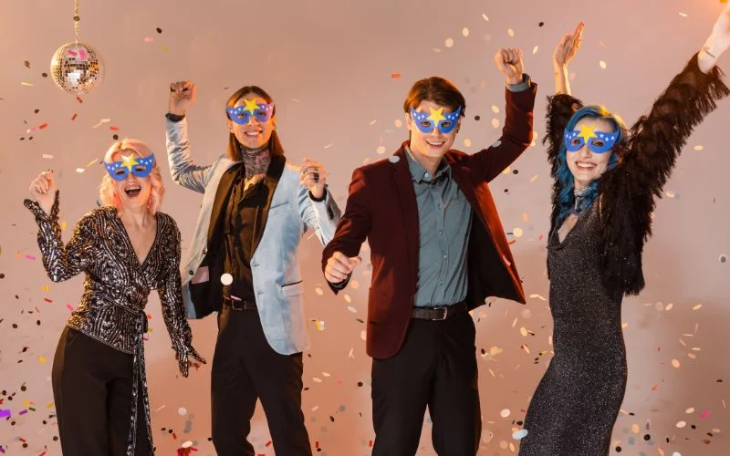 Candid prom photography pose of friends celebrating with confetti and sunglasses
