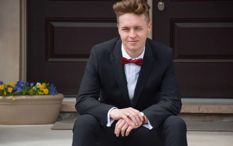 Prom picture pose for guys with a young man seated on outdoor steps in a tux