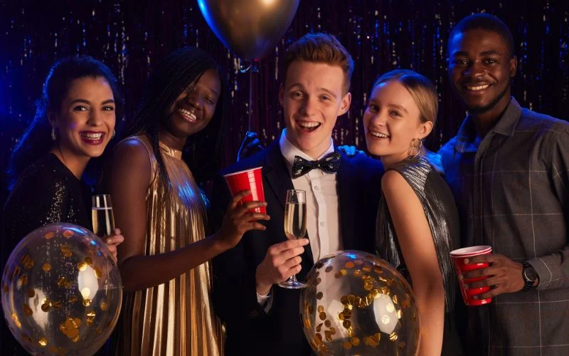 Prom picture poses for friends with a group raising drinks together at prom