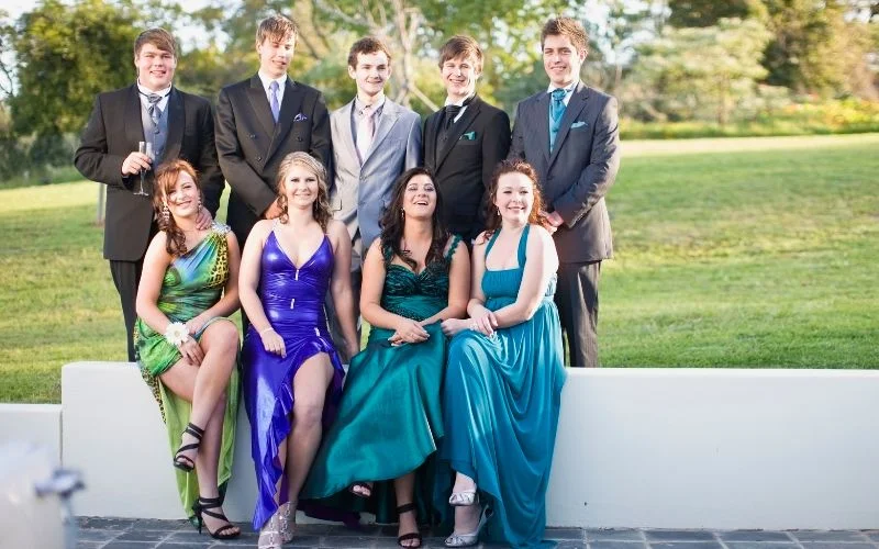 Group prom poses of a group of friends seated and standing together outdoors